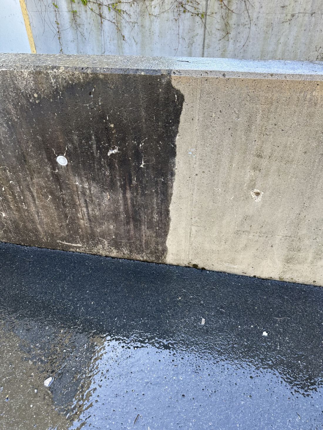 Betonmauer zur Hälfte mit Hochdruck gereinigt: links verschmutzt, rechts sauber